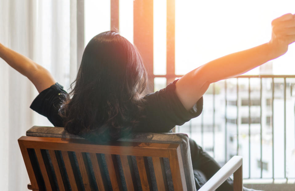 A woman stretching while looking out her window