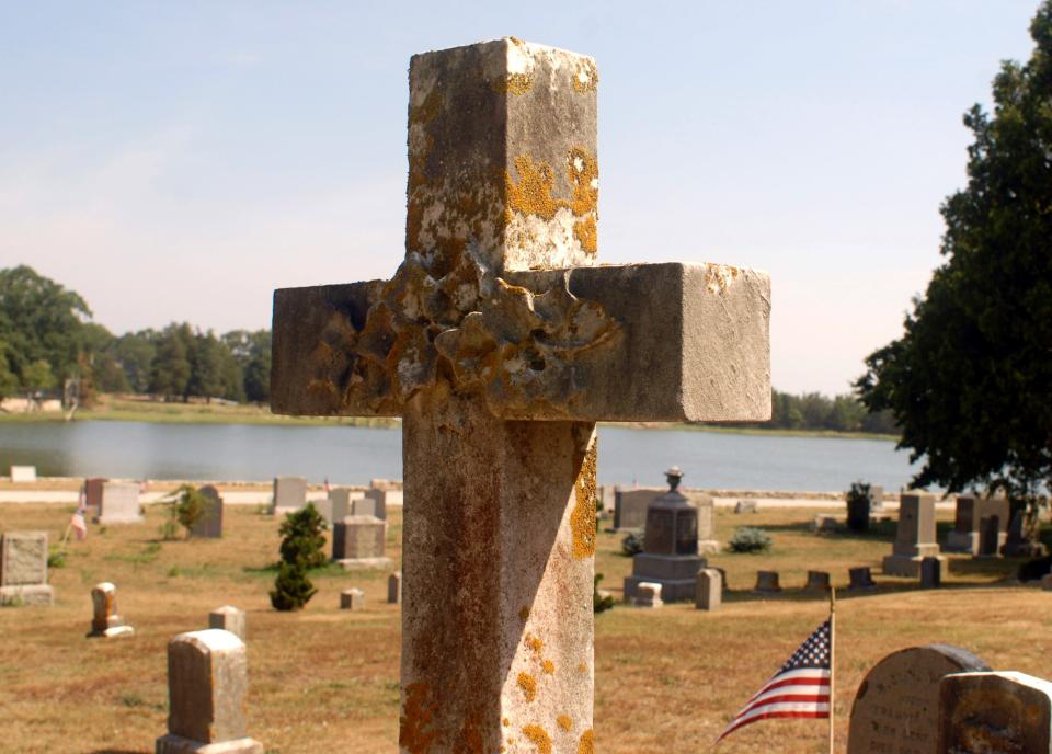 A stone cross covered in lichen marks a grave at Cohasset Central Cemetery, which experienced flooding to the point that nearly 150 graves were impacted.