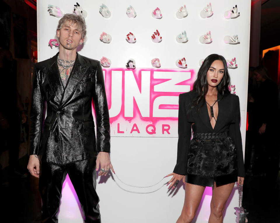 Machine Gun Kelly and Megan stand a few feet apart and show off the chain