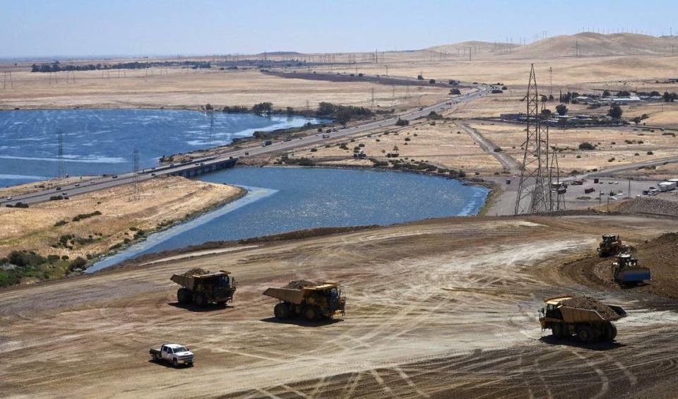 Looking down from the top of the B.F. Sisk dam, heavy machinery is seen preparing the ground with O’Neill Forebay and Highway 152 seen in the background Thursday, Aug. 8, 2024 near Los Banos.