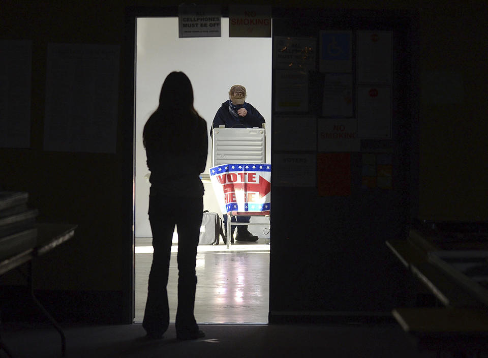 First-time voter Baylee Fidler, 19, waits in the doorway for a voting booth as Tom Davis, background, completes his ballot at the Boot City Opry near Terre Haute, Ind., on Tuesday, Nov. 3, 2020. As the 2022 midterm elections enter their final two-month sprint, leading Republicans concede that their party's advantage may be slipping even as Democrats confront their president's weak standing, deep voter pessimism and the weight of history this fall. (Joseph C. Garza/The Tribune-Star via AP)