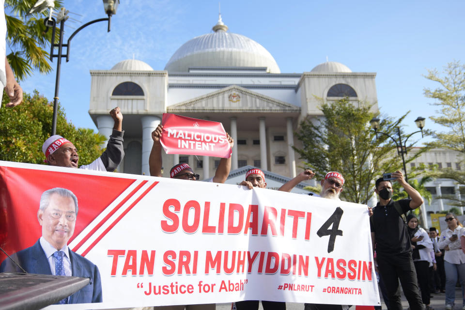 Supporters hold a banner with Malaysia's former Prime Minister Muhyiddin Yassin picture to show support outside courthouse during a corruption charges in Kuala Lumpur, Malaysia, Friday, March 10, 2023. Muhyiddin, who led Malaysia from March 2020 until August 2021, will be the country's second leader to be indicted after leaving office. (AP Photo/Vincent Thian)