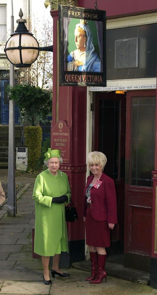 <p>Her Majesty drops in on the Eastenders set at Elstree Studios. Here she stands outside the Queen Victoria pub with actress and longstanding cast member Barbara Windsor. (PA Archive) </p>