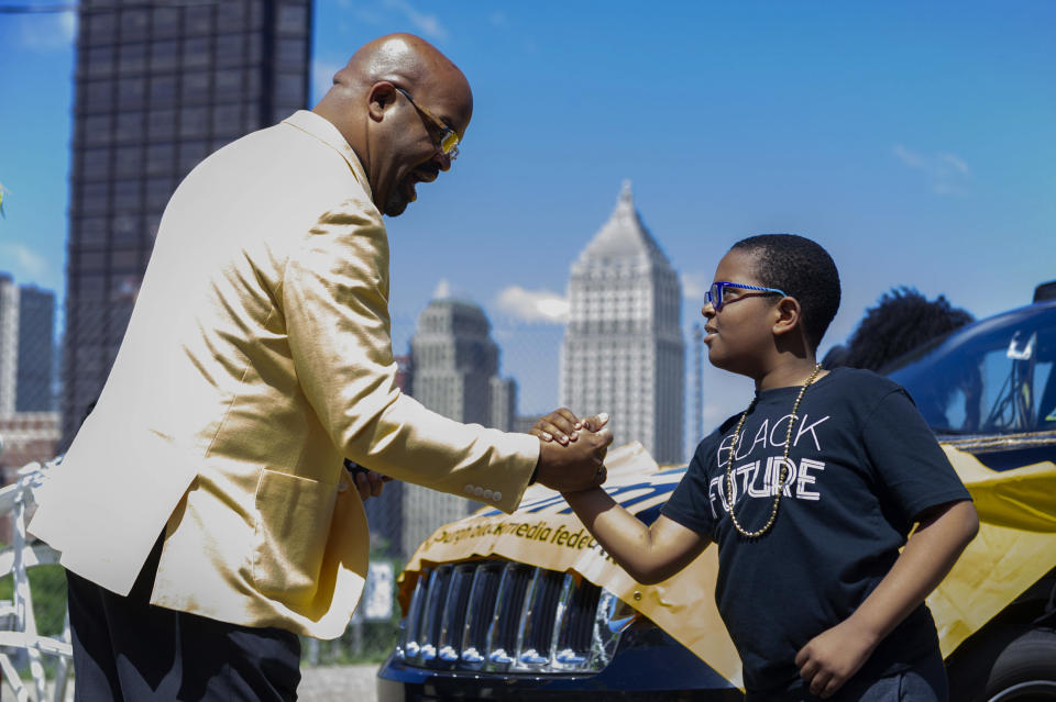 Darren McCormick, an Alpha Phi Alpha Pittsburgh Chapter member, teaches a handshake to Brian Cook Jr., during the Juneteenth Voting Rights Parade lineup on Saturday, June 18, 2022, in Pittsburgh. Cook's father, Brian Cook, is the President of the Pittsburgh Black Media Federation, who joined Alpha Phi Alpha, Pittsburgh, and Alpha Omicron Lambda, of Pittsburgh University, in support of Sunday's holiday. On Saturday, community groups and leaders marched in the Juneteenth Voting Rights Parade from Freedom Corner to Point State Park. (Ariana Shchuka/Pittsburgh Post-Gazette via AP)