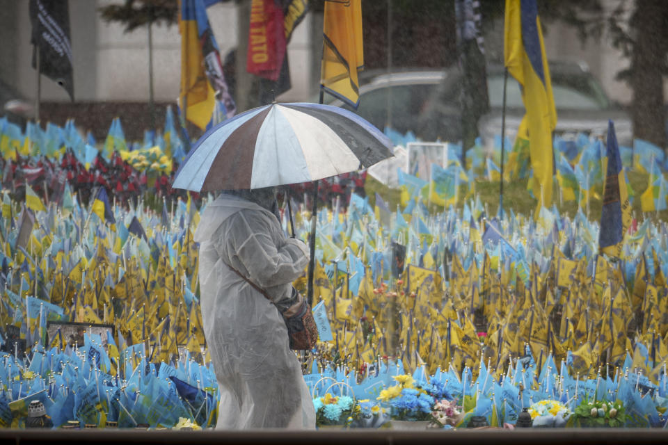 圖為烏克蘭基輔市中心，一名婦女走過懸掛在陣亡士兵紀念碑前的烏克蘭國旗。（美聯社）