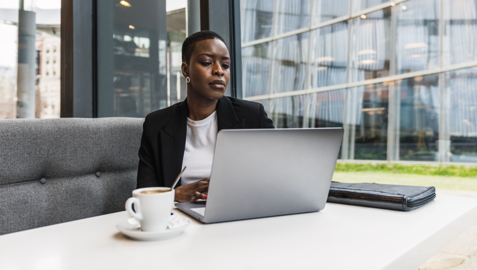 a person sitting at a table with a laptop and coffee