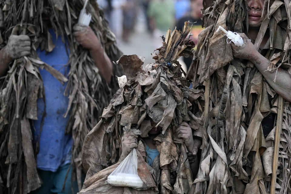 A devout Catholic holds the hand of a child as they walk towards the church of Saint John the Baptist during the mud festival at Bibiclat, Nueva Ecija province, northern Philippines, Monday, June 24, 2024. (AP Photo/Aaron Favila)