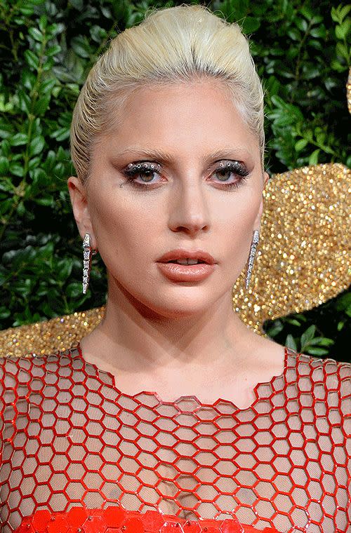 Gaga always goes beyond what is expected, especially when it comes to makeup. We are digging her dazzling jeweled lids, long fluttery lashes and glossy orange nude lips she’s flaunting at the British Fashion Awards in London.