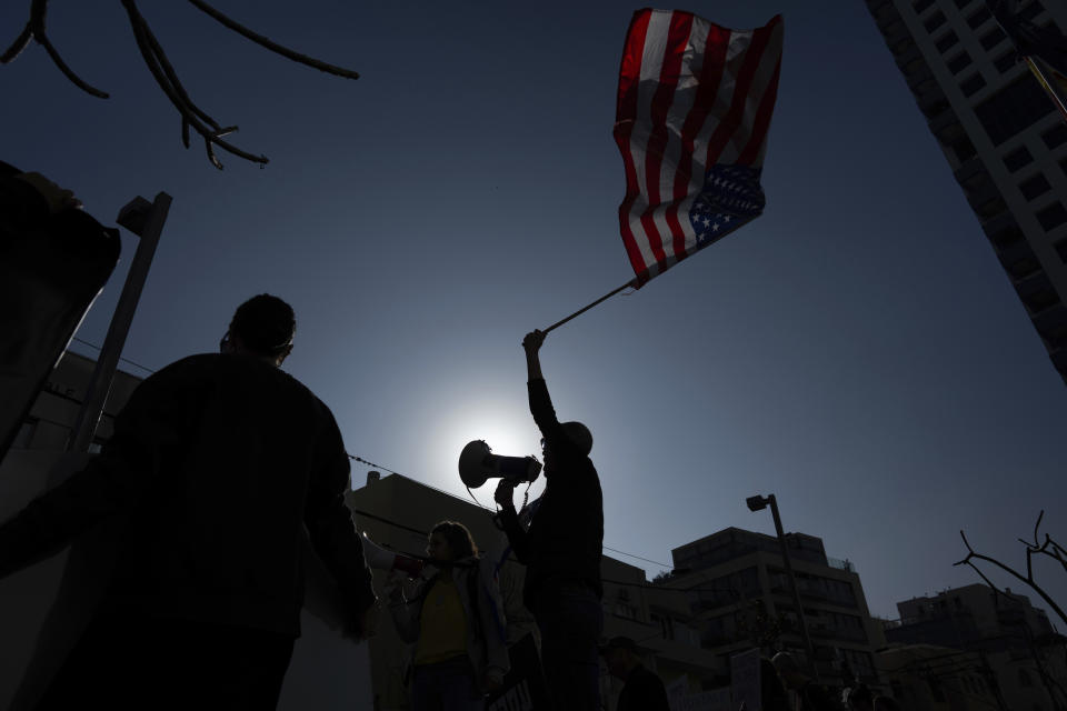 A family member of Israeli hostages held by Hamas in Gaza waves the U.S. flag at a protest calling for their return, outside a meeting between U.S. Secretary of State Antony Blinken and Israeli President Isaac Herzog, in Tel Aviv, Israel, Tuesday, Jan. 9, 2024. More than 100 Israeli hostages are held in Gaza after being abducted in a Hamas cross-border attack on Oct. 7. (AP Photo/Oded Balilty)