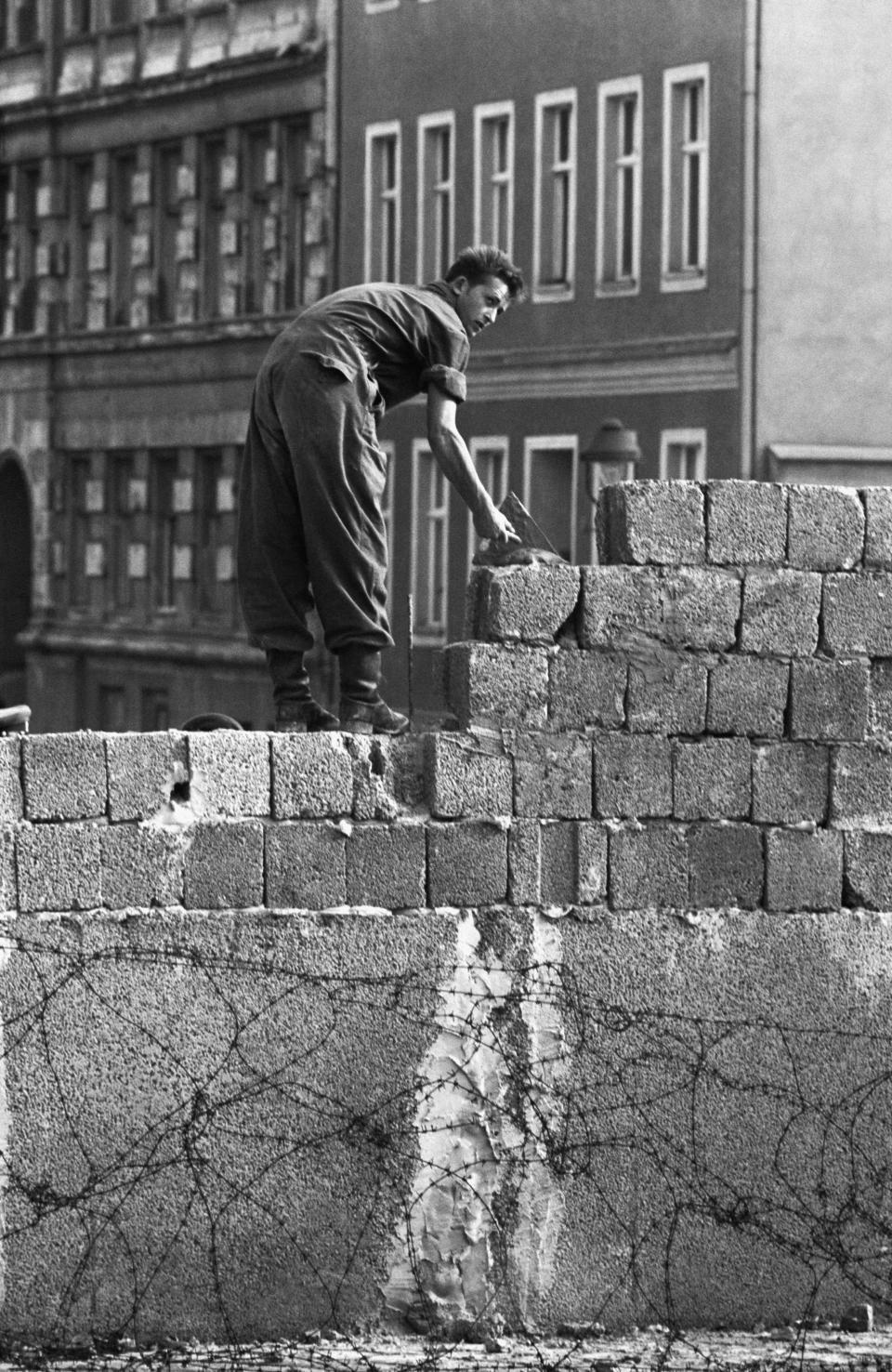 21/11/1961- An East German construction worker helps construct the Berlin Wall near the Brandenburg Gate. Picture- Corbis Images