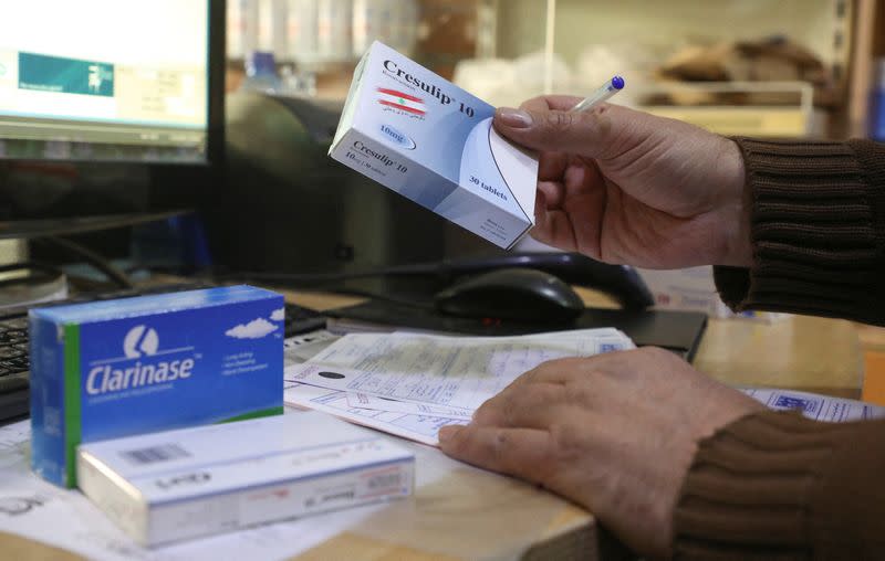 Yassin Fala, a pharmacist, holds a box of medication at his pharmacy in Beirut