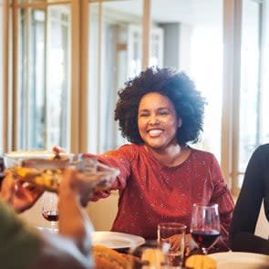 Smiling woman passing food to friend at thanksgiving party