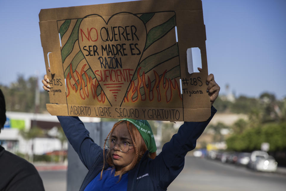 A member of the reproductive rights organization "Colectiva Bloodys y Projects" holds a sign that reads in Spanish "Not wanting to be a mother is reason enough. Free, safe abortion," outside a public hospital in Tijuana, Mexico, Thursday, Sept. 28, 2023. The organization, which has supported reproductive rights near the U.S.-Mexico border since 2016, is made of up dozens of Mexican volunteers who support women wanting to terminate a pregnancy, offering virtual guidance through an abortion protocol in which no clinics or prescriptions are needed. (AP Photo/Karen Castaneda)