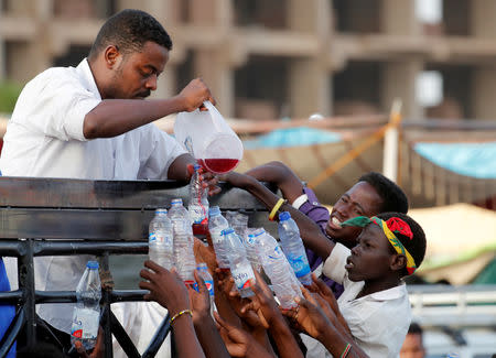 A Sudanese man offers juice to demonstrators as they protest in front of the Defence Ministry in Khartoum, Sudan April 17, 2019. REUTERS/Umit Bektas