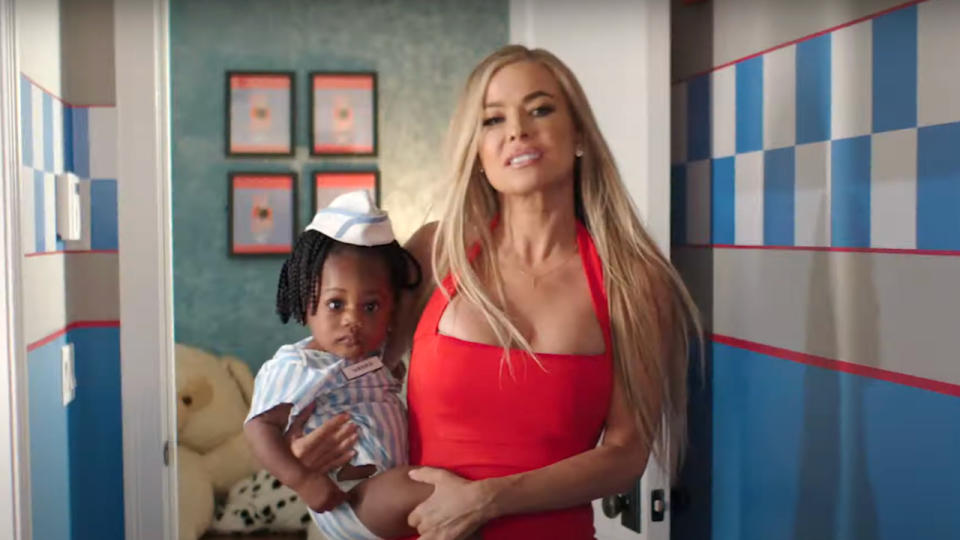 Carmen Electra holding a little baby while walking down the hall in Good Burger 2.