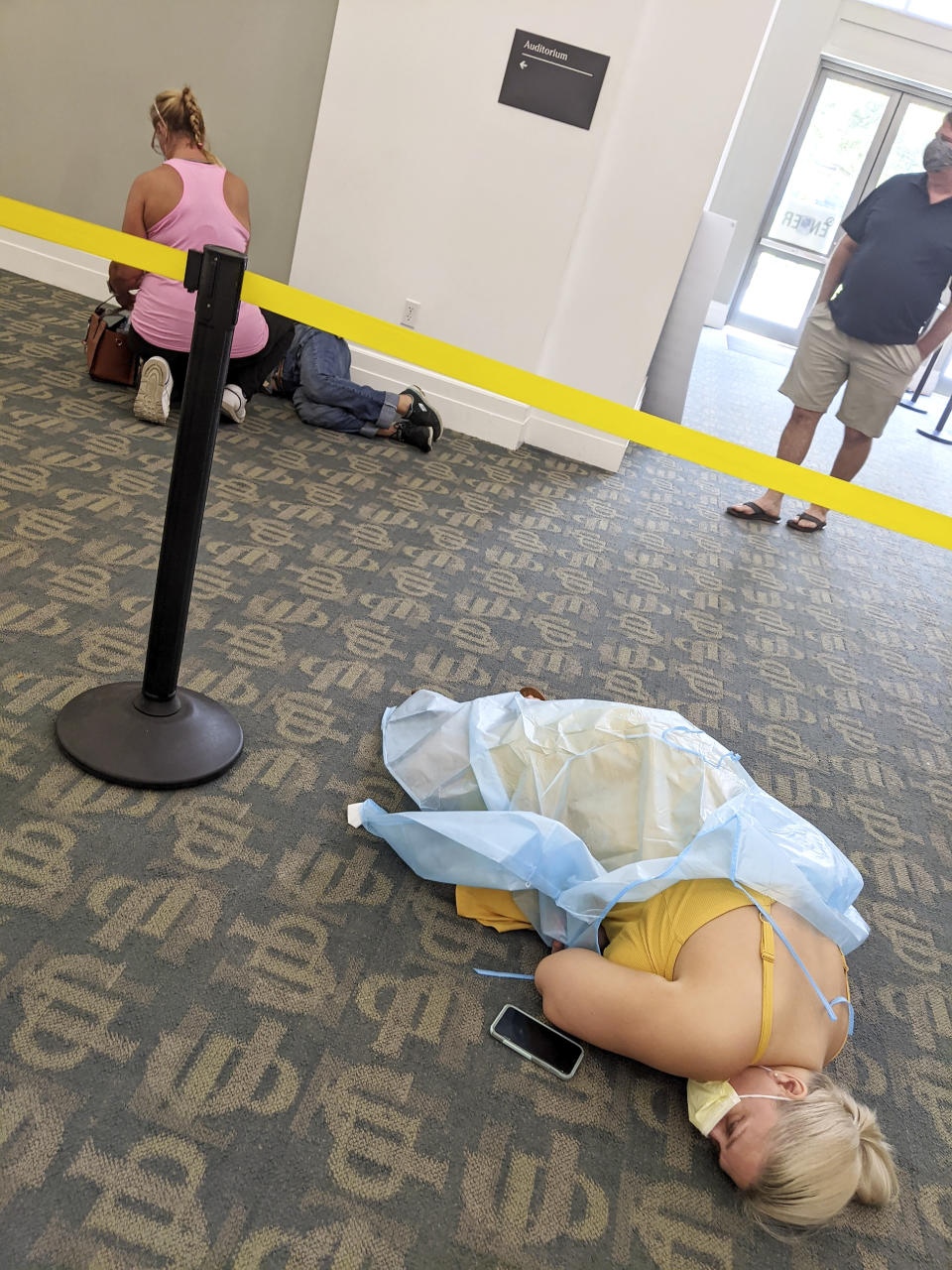 In this photo provided by Louie Lopez, sick people lie on the floor in a medical facility in Jacksonville, Fla., on Wednesday, Aug. 18, 2021. Lopez took the photo while waiting more than 2.5 hours to get antibody treatment at a facility run by the state. While he waited, he watched the room fill up with extremely sick patients. (Louie Lopez via AP)