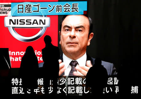 Passersby are silhouetted as a huge street monitor broadcasts news reporting ousted Nissan Motor chairman Carlos Ghosn's indictment and re-arrest in Tokyo, Japan December 10, 2018. REUTERS/Issei Kato