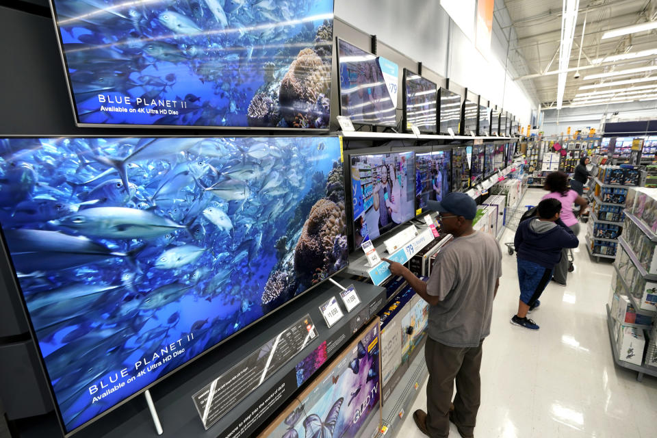 FILE- In this Nov. 9, 2018, file photo shoppers look at televisions at a Walmart Supercenter in Houston. Super Bowl season is an excellent time to purchase a new TV, as long as you have room in your home and budget. (AP Photo/David J. Phillip, File)
