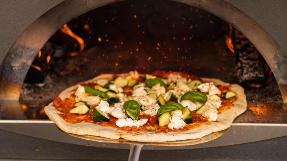 Pizza entering a wood fire pizza oven