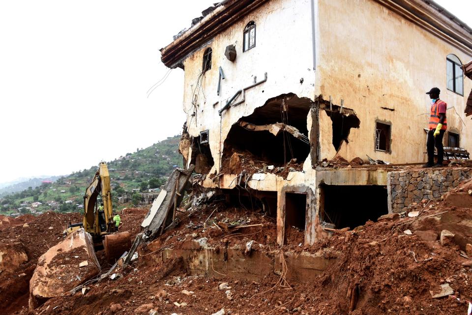 <p>A man watches as a digger is used to clear mud and debris following the partial collapse of a hillside earlier in the week that swept away hundreds of homes in a neighborhood of the capital Freetown on Aug. 19, 2017. (Photo: Seyllou/AFP/Getty Images) </p>