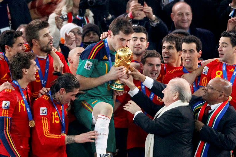 El presidente de FIFA Sepp Blatter y el presidente sudafricano Jacob Zuma entregan el trofeo de la Copa Mundial al capitán del equipo español Iker Casillas (C) durante la ceremonia de entrega de premios en el estadio Soccer City en Johannesburgo el 11 de julio de 2010.