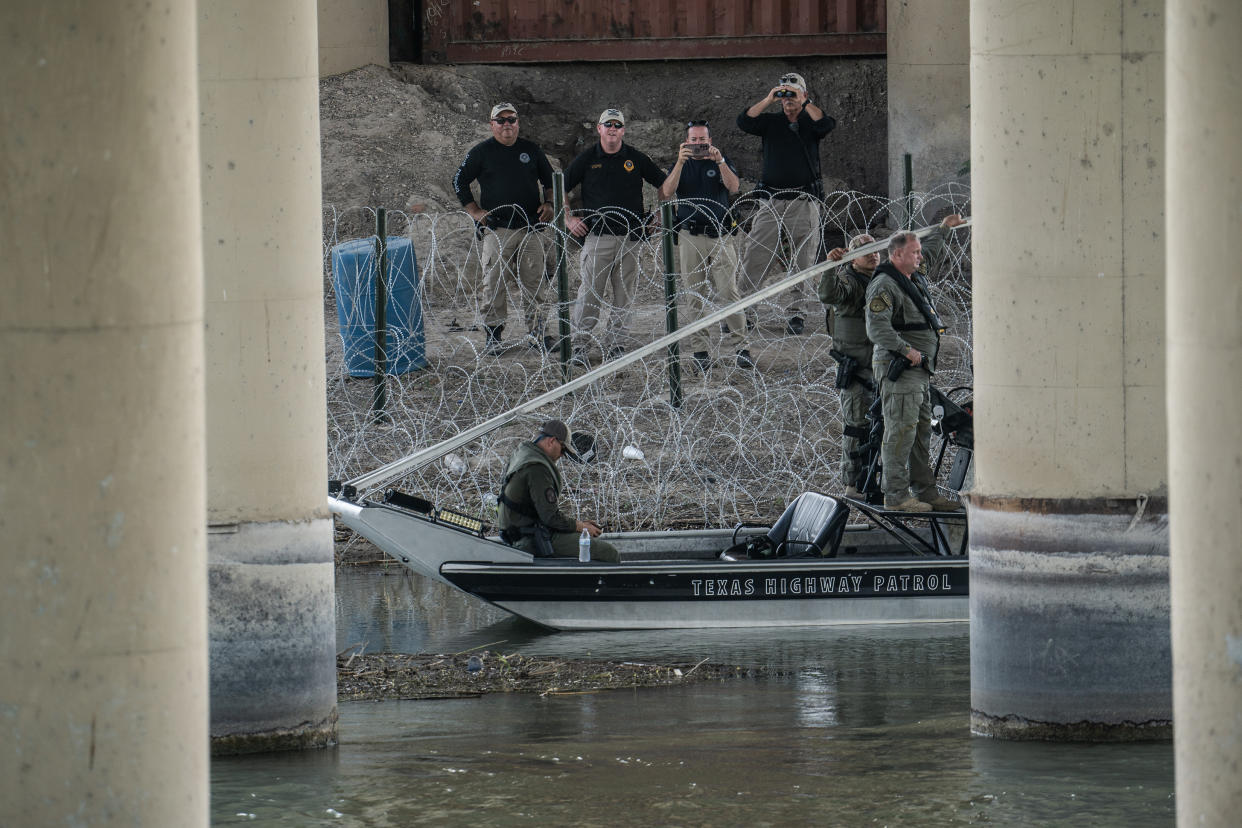 Agentes de la ley de Texas de guardia junto un alambre de púas en la orilla del río Bravo en Eagle Pass, Texas, el 19 de julio de 2023. (Go Nakamura/The New York Times)