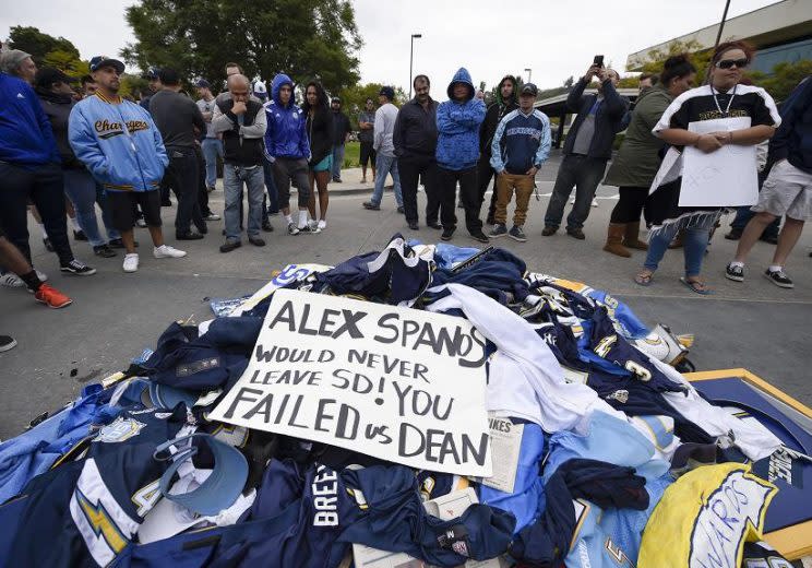 Disappointed fans stand around a pile of Chargers memorabilia in front of the team's old headquarters. (AP)