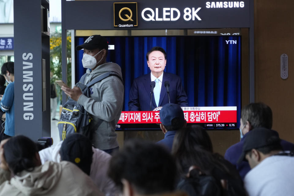 People watch a TV screen showing the live broadcast of South Korean President Yoon Suk Yeol’s addressing the nation at the Seoul Railway Station in Seoul, South Korea, Monday, April 1, 2024. President Yoon vowed Monday not to back down in the face of vehement protests by doctors seeking to spike his plan to drastically increase medical school admissions, as he called their walkouts “an illegal collective action” that poses "a grave threat to our society.” (AP Photo/Ahn Young-joon)