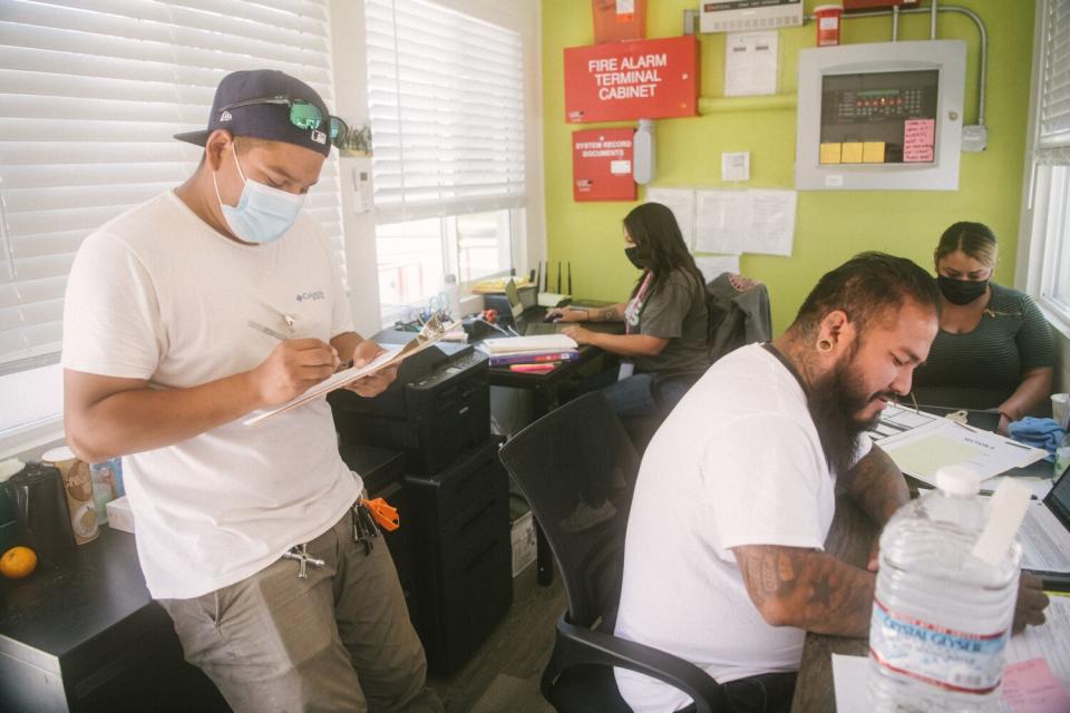 Four people work inside an office that is painted green.