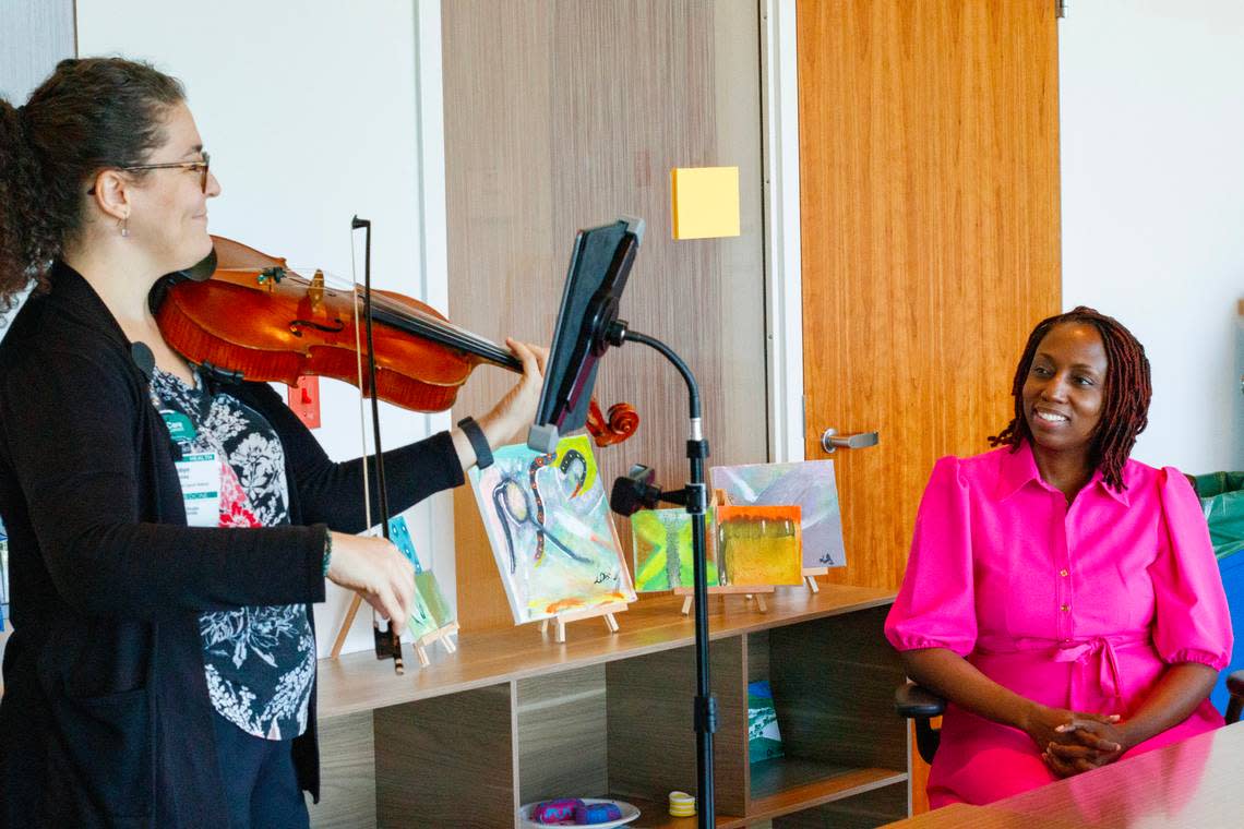 Breast cancer survivor Latoya Simmons, 42, listens as Robyn Savitzky, a viola performer and artist in residence at Baptist Hospital, plays “How Far I’ll Go” from Disney’s “Moana” on Thursday, Oct. 5, 2023. Savitzky is one of the musicians cancer patients can request to play music for them while they undergo treatment at the Miami Cancer Institute..