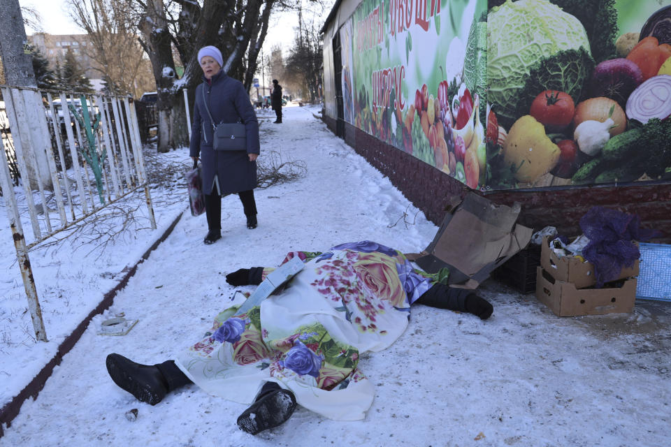 A woman walks past a body of a victim killed during the shelling that Russian officials in Donetsk said was conducted by Ukrainian forces, in Donetsk, Russian-controlled Donetsk region, eastern Ukraine in Donetsk, Ukraine, Sunday, Jan. 21, 2024. Local officials say at least 18 people have been killed by shelling of a market in Russian-occupied Ukraine. The attack hit Tekstilshchik, a suburb of the city of Donetsk, on Sunday. Alexei Kulemzin, the city's Russian-installed mayor, said that the shells had been fired by the Ukrainian military. (AP Photo/Alexei Alexandrov)