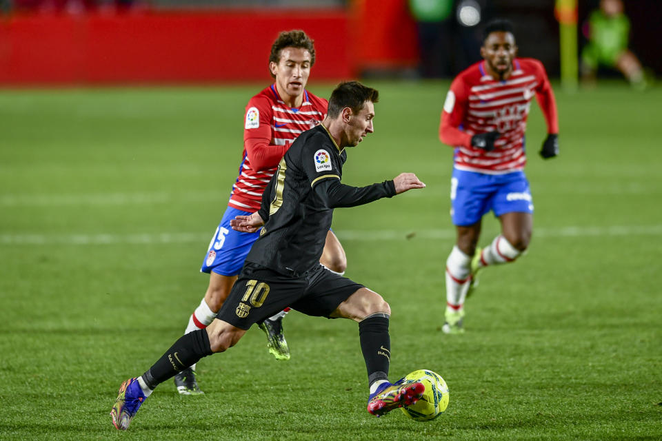 Lionel Messi, del Barcelona, disputa el balón con Luis Milla del Granada en partido por La Liga española en el estadio Los Cármenes, Granada, España, sábado 9 de enero de 2021. Barcelona se impuso 4-0 con dobletes de Messi y Antoine Griezmann. (AP Foto/Jose Breton)