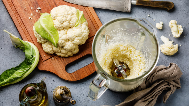 Cauliflower in blender next to cutting board