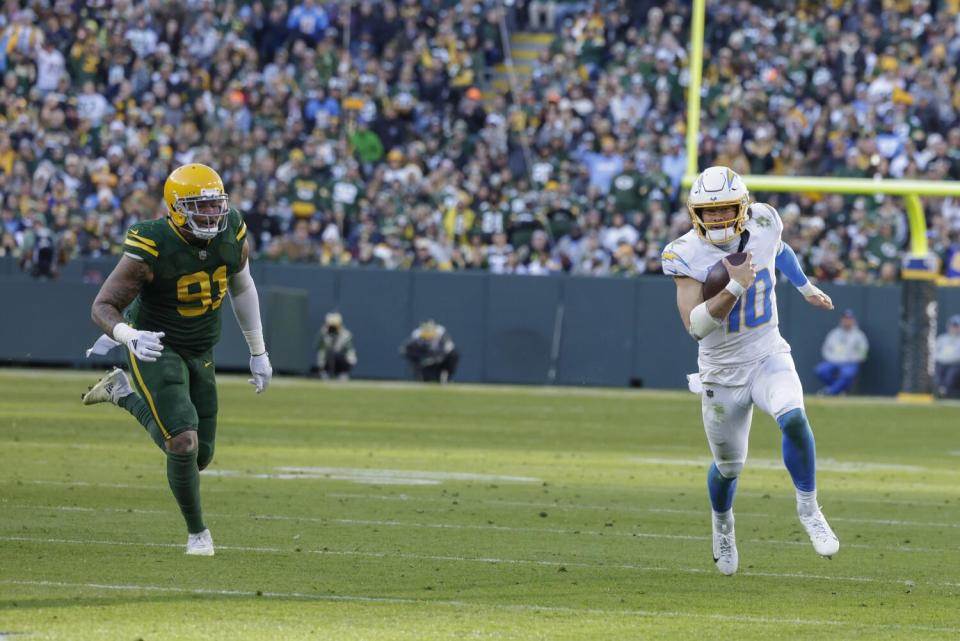 Chargers quarterback Justin Herbert (10) runs past Green Bay Packers linebacker Preston Smith (91).