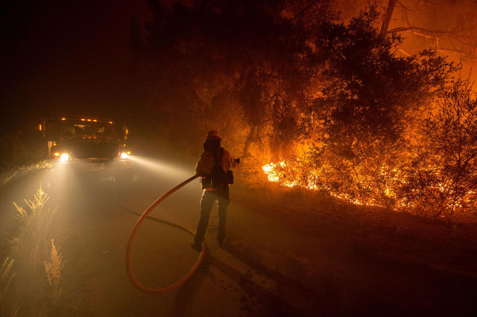 <p>Sampson Spence of Fremont Fire douses flames as they approach a road in the Santa Cruz Mountains near Loma Prieta, California on September 28, 2016. The Loma Fire has charred more than 2000 acres and burned multiple structures in the area. (Josh Edelson/AFP/Getty Images) </p>