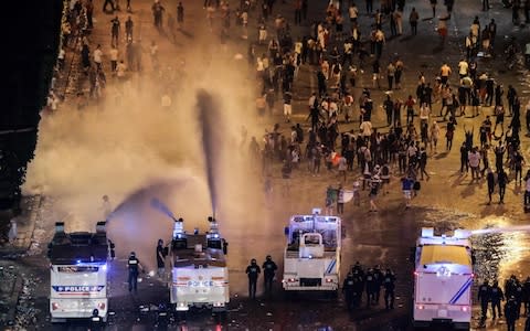 Police disperse people with water cannons on the Champs-Elysees after celebrations following the Russia 2018 World Cup final - Credit: AFP