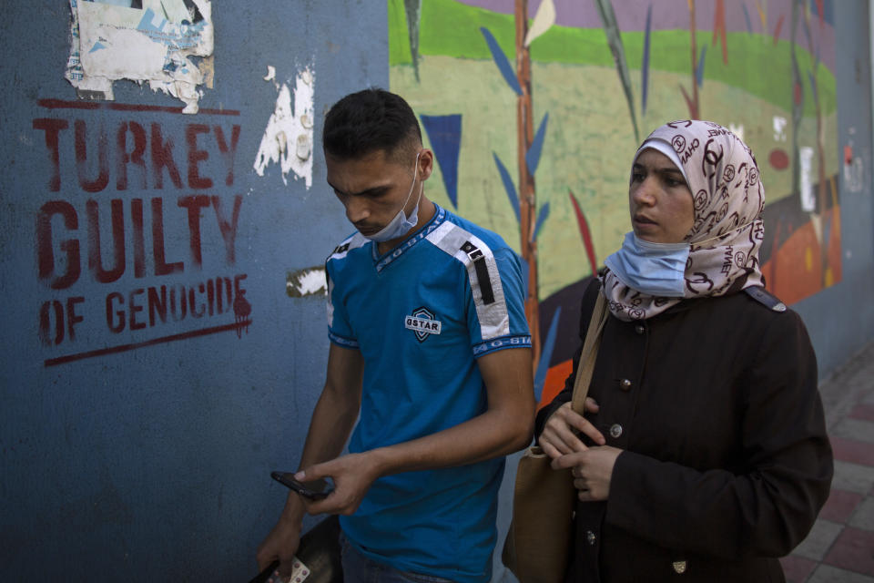 People walk past anti-Turkish graffiti on a wall in the main Armenian district of the northern Beirut suburb of Bourj Hammoud, Lebanon, Tuesday, Oct. 6, 2020. In Bourj Hammoud anger and anxiety are clear among the population over the fighting between Armenian and Azerbaijani forces in the separatist region of Nagorno-Karabakh that broke out on Sept. 27 and has left dozens killed since then. Hundreds of fighters from around the Middle East are heading to Nagorno-Karabakh in Azerbaijan to join rival countries fighting over the region. (AP Photo/Hassan Ammar)