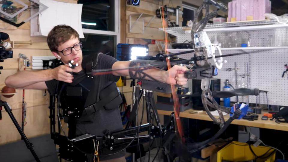 An engineer using an auto-aiming robotic bow and arrow to fire at a target.