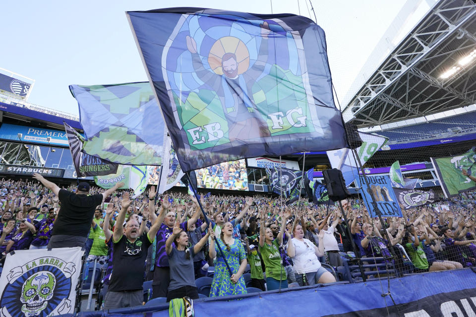 FILE - In this July 25, 2021, file photo, members of the Emerald City Supporters and other fans wave flags and cheer before an MLS soccer match between the Seattle Sounders and Sporting Kansas City in Seattle. Fans attending most pro sporting events in Seattle will soon be required to show proof they've been vaccinated against COVID-19 or that they've tested negative for the virus. The NFL's Seahawks, MLS's Sounders, NHL's Kraken and the University of Washington all announced updated policies Tuesday, Sept. 7, 2021, for fans attending games this season. (AP Photo/Ted S. Warren, File)