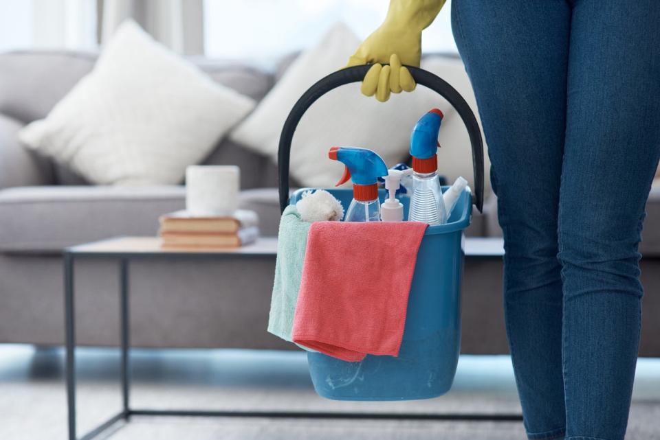 A cleaner holds a bucket a cleaning products. 