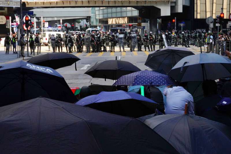香港「反送中」抗爭者（持雨傘的群眾）11日在街頭與警察對峙。（美聯社）