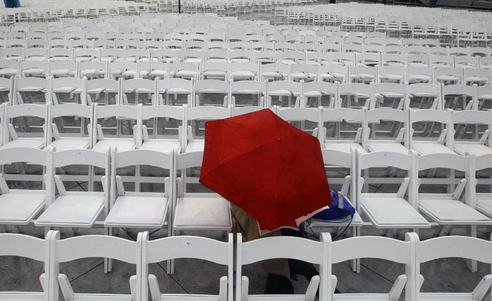 A person sits alone reading a magazine in the rain at MetLife stadium in East Rutherford, N.J, Wednesday, Aug. 1, 2012, as he waits for the start of the celebration Siyum HaShas. The Siyum HaShas, marks the completion of the Daf Yomi, or daily reading and study of one page of the 2,711 page book. The cycle takes about 7½ years to finish.This is the 12th put on my Agudath Israel of America, an Orthodox Jewish organization based in New York. Organizers say this year's will be, by far, the largest one yet. More than 90,000 tickets have been sold, and faithful will gather at about 100 locations worldwide to watch the celebration. (AP Photo/Mel Evans)