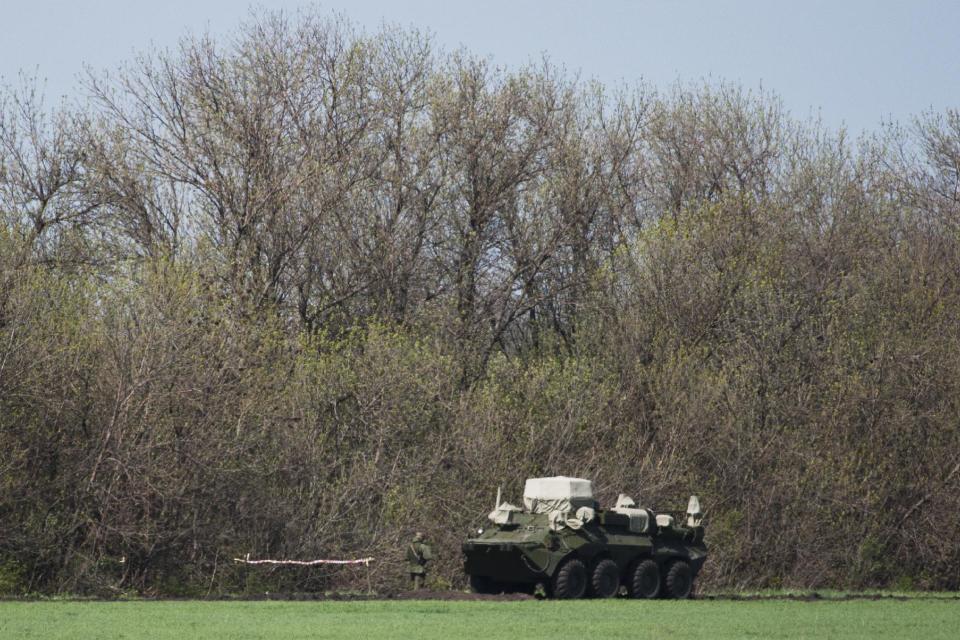 Russian solder patrols near army vehicle in a field about 2 kilometers (1.24 miles) from the Ukrainian border at Novoshakhtinsk, Rostov region, Russia, Monday, April 28, 2014. (AP Photo/Pavel Golovkin)