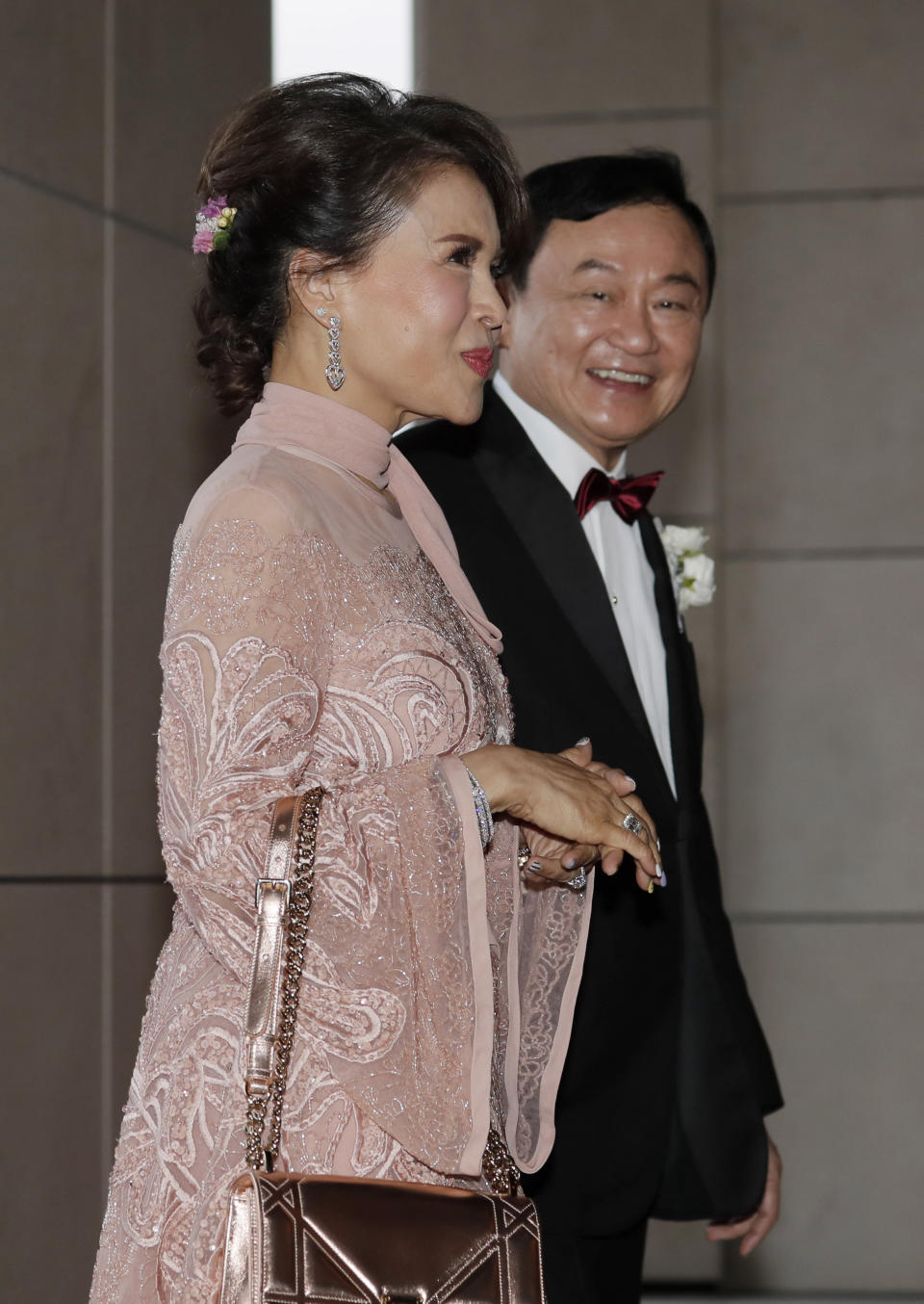 Former Thai Prime Minister Thaksin Shinawatra, right, walks with Princess Ubolratana of Thailand as they arrive the wedding of his youngest daughter Paetongtarn "Ing" Shinawatra at a hotel in Hong Kong, Friday, March 22, 2019. (AP Photo/Kin Cheung)