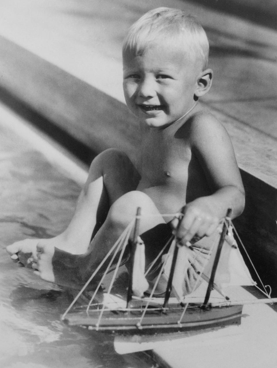 A Young Skipper. Buzz Aldrin, of Montclair, N.J., tries the water for temperature before setting sail at Miami Beach, Fla., where his parents spent a winter vacation.