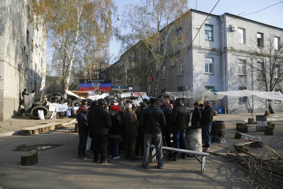 People gather in front of a barricade across a street in Slovyansk, eastern Ukraine, Wednesday, April 16, 2014. The city of Slovyansk has come under the increasing control of the pro-Russian gunmen who seized it last weekend. The writing on the flag on top of the barricade reads : "Donetsk Republic." (AP Photo/Sergei Grits)