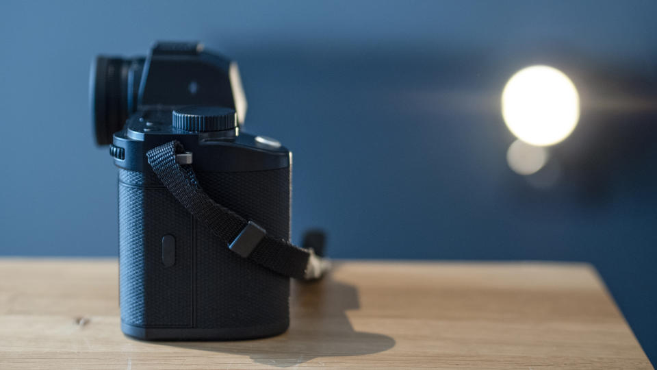 Leica SL3 camera on a wooden surface against a blue background