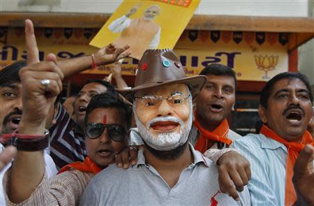 A supporter wearing a mask of Gujarat's chief minister and Hindu nationalist Narendra Modi, the prime ministerial candidate for India's main opposition Bharatiya Janata Party (BJP), celebrates outside the party's headquarters in the western Indian city of Ahmedabad December 8, 2013. REUTERS/Amit Dave