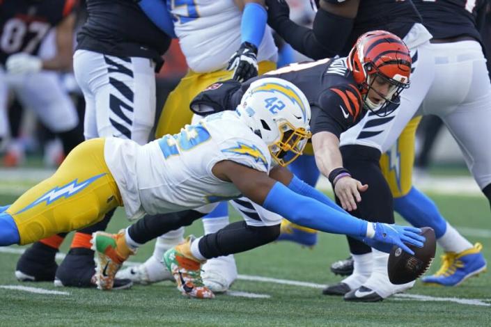 Los Angeles Chargers&#39; Uchenna Nwosu (42) and Cincinnati Bengals quarterback Joe Burrow (9) dive for a fumble by Burrow during the first half of an NFL football game, Sunday, Dec. 5, 2021, in Cincinnati. Nwosu recovered the fumble. (AP Photo/Michael Conroy)