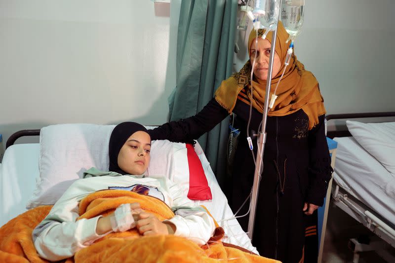 Nahida Mashouz, a refugee woman from Syria, stands next to her injured daughter at a governmental hospital in Marjayoun